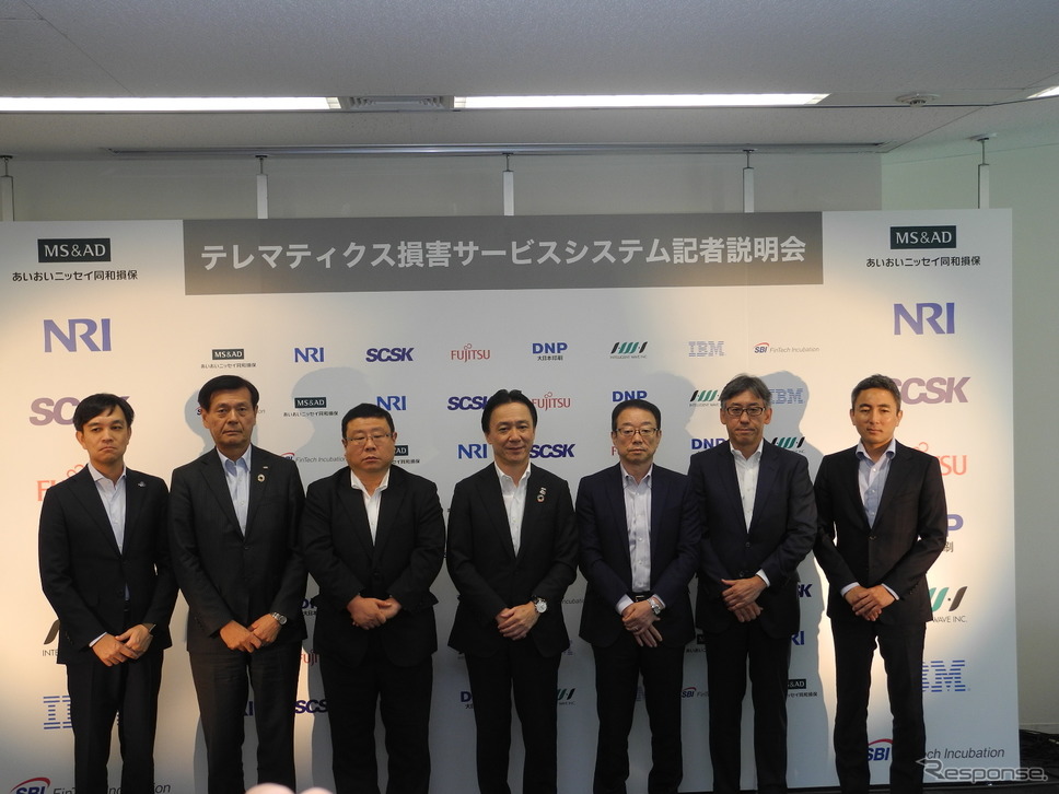 「テレマティクス損害サービスシステム」を共同で開発した8社の幹部。中央があいおいニッセイ同和損害保険の樋口昌宏取締役専務執行役員《撮影 山田清志》