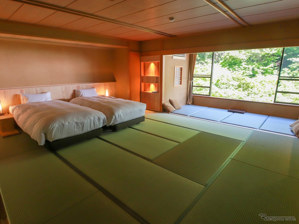 純和風の部屋の面影を残す居間の畳、そこに快適な睡眠の時を過ごせるようベッドを配置。ベッドサイドにはアンティーク風の照明。《画像提供 扉ホールディングス株式会社》