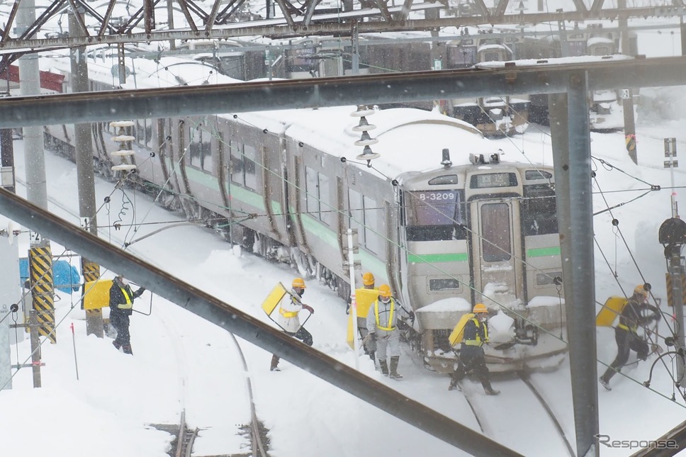スノーダンプを担ぎ、除雪作業に入る人々。2022年2月22日、函館本線小樽駅。《写真撮影 佐藤正樹》