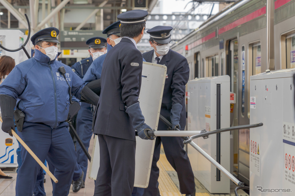 飛田給駅で緊急停車した電車に、警察官と駅員がさすまたや警棒、防護シールドを持って乗り込む。《写真撮影 関口敬文》