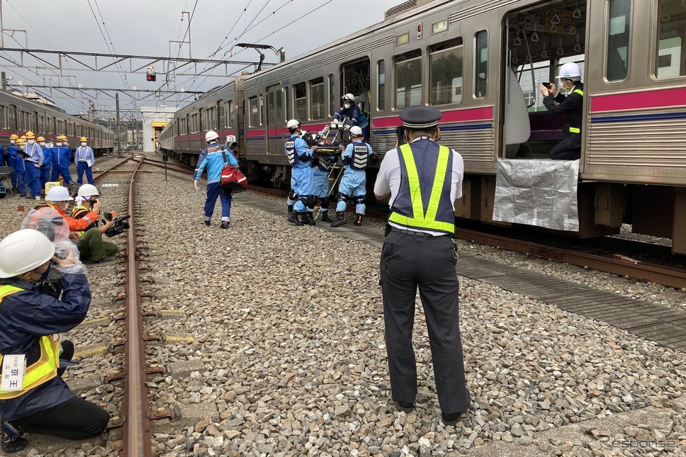京王電鉄・総合事故復旧訓練：重傷者の搬送。写真中央、背中の人物はバディコムを使用中だ。《写真撮影 高木啓》
